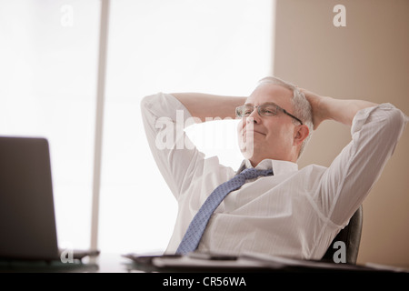 Kaukasische Geschäftsmann sitzen am Schreibtisch mit Händen auf Kopf Stockfoto