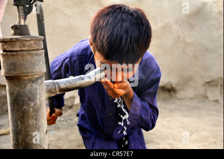 Junge Trinkwasser aus einem Brunnen mit einer Handpumpe, Dorf von Basti Lehar Walla, Punjab, Pakistan, Asien Stockfoto