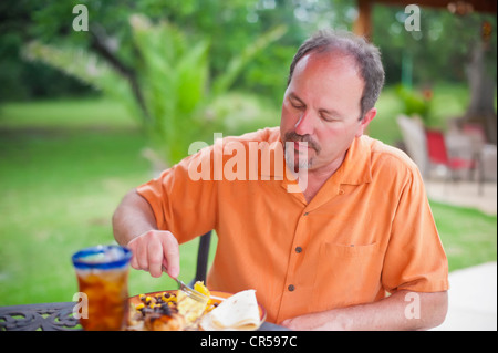 Mann isst im Hinterhof Grill Stockfoto