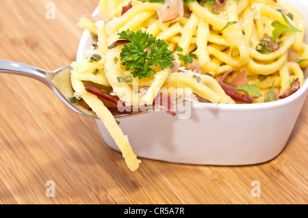 Käse-Spätzle mit Anteil an Gabel auf hölzernen Hintergrund Stockfoto