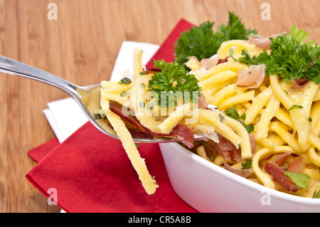 Käse-Spätzle in einer Schüssel mit Anteil an Gabel (auf hölzernen Hintergrund) Stockfoto