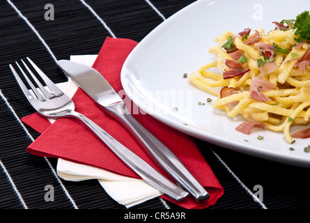 Portion frische Käse-Spätzle mit frischen Kräutern auf schwarze Tischdecke dekoriert Stockfoto