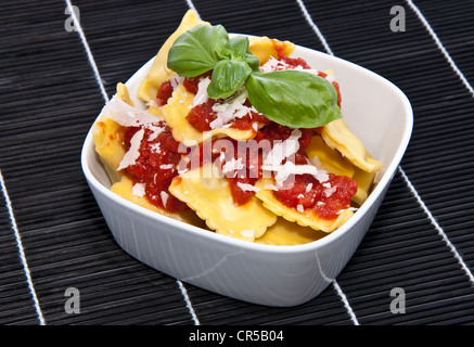 Portion Frische Ravioli in einer Schüssel auf einem schwarzen Tischdecke Stockfoto