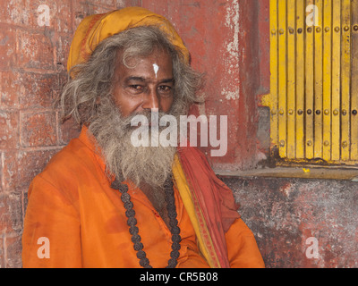 Ein Sadhu, heiliger Mann von Indien, sitzt vor einem kleinen Schrein in den Straßen von New Delhi Stockfoto