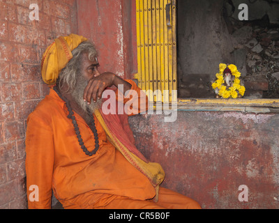 Ein Sadhu, heiliger Mann von Indien, sitzt vor einem kleinen Schrein in den Straßen von New Delhi, Neu Delhi, Indien, Asien Stockfoto