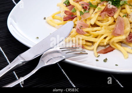 Portion frische Käse-Spätzle mit frischen Kräutern auf schwarze Tischdecke dekoriert Stockfoto