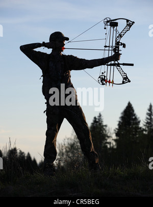 Silhouette eines modernen Bogen Jägers Zeichnung Bogen zurück im Wald Stockfoto