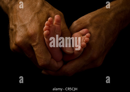 Des Vaters Hände halten Babys Füße Stockfoto