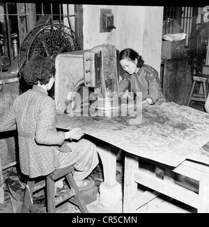 Hongkong, 1950er, zwei chinesische Arbeiterinnen in einer kleinen Fabrik, die eine alte Druckmaschine benutzten. Stockfoto