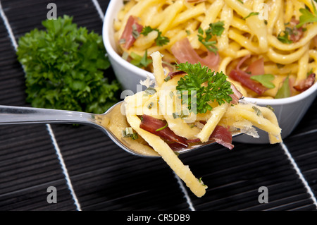 Portion Käse Spätzle in einer Schüssel mit Anteil an Gabel (auf schwarze Tischdecke) Stockfoto