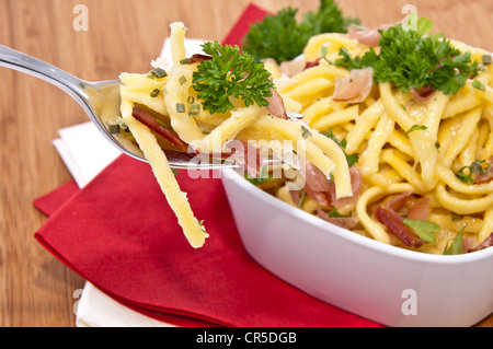 Käse-Spätzle in einer Schüssel mit Anteil an Gabel (auf hölzernen Hintergrund) Stockfoto