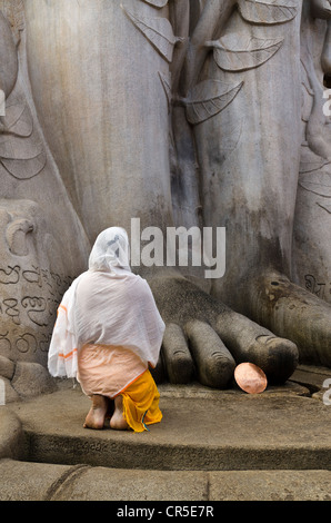 Jain Pilger beten ist an den Füßen der Statue von Lord Gomateshwara, der höchste monolithische Statue der Welt, engagierte Stockfoto