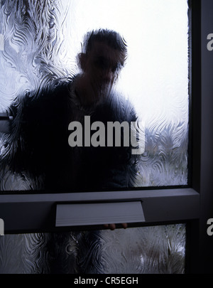 Silhouette eines Mannes hinter einer Milchglas-Tür, außerhalb im Blick. Gestellt von Modellen Stockfoto