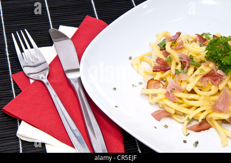 Portion frische Käse-Spätzle mit frischen Kräutern auf schwarze Tischdecke dekoriert Stockfoto