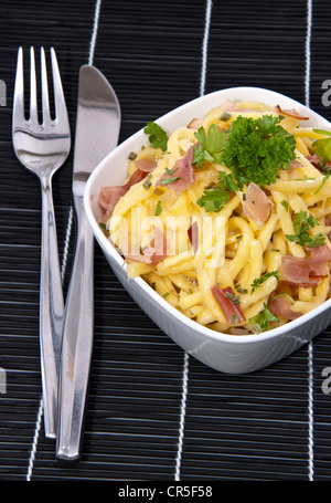 Portion Käse Spätzle dekoriert mit frischen Kräutern auf schwarze Tischdecke Stockfoto