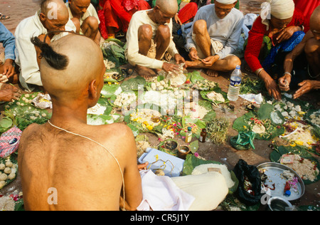 Ein Priester unterstützt eine betende Ritual für die gute Reinkarnation eines verstorbenen an Har Ki Pauri Ghat in Haridwar Stockfoto