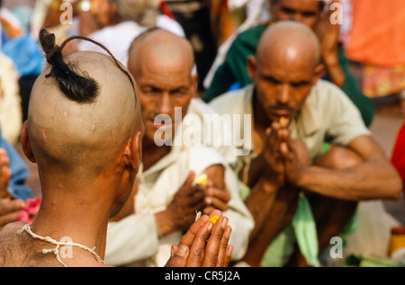 Ein Priester unterstützt eine betende Ritual für die gute Reinkarnation eines verstorbenen an Har Ki Pauri Ghat in Haridwar Stockfoto