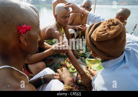 Ein Priester unterstützt eine betende Ritual für die gute Reinkarnation eines verstorbenen an Har Ki Pauri Ghat in Haridwar Stockfoto