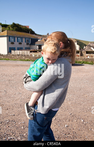 Mutter trägt einen zwei Jahre alten Jungen, Hope Cove, Devon, England, Vereinigtes Königreich. Stockfoto