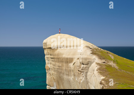 Touristen auf Klippe am Tunnel Beach, Dunedin, Südinsel, Neuseeland Stockfoto