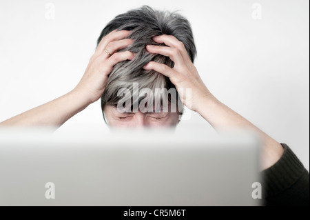 Betonte Frau saß hinter einem Computer-Bildschirm an den Haaren reißen Stockfoto
