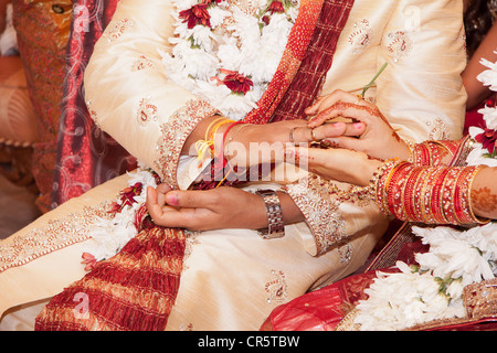 Indische Braut vorbei Ehering am Finger von ihrem Bräutigam Stockfoto