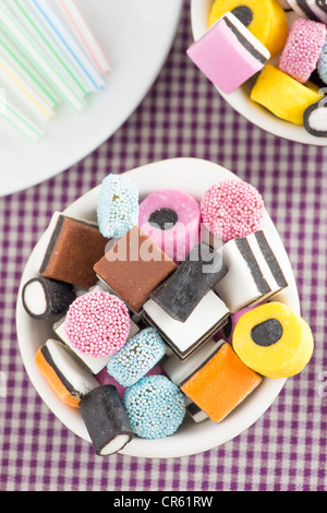 Schüsseln gefüllt mit Lakritz-Bonbons und Trinkhalme Stockfoto