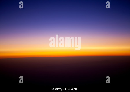 Blick auf den Sonnenuntergang über den Wolken von Flugzeugfenster gesehen Stockfoto