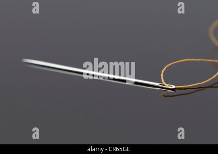 Nahaufnahme von Nadel und Gold Thread auf reflektierenden schwarzen Hintergrund Stockfoto