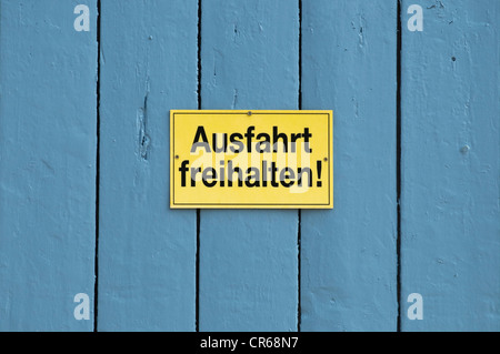 Zeichen, Kreuzstrasse Freihalten oder halten Sie Exit klar, auf eine blaue Tür Stockfoto