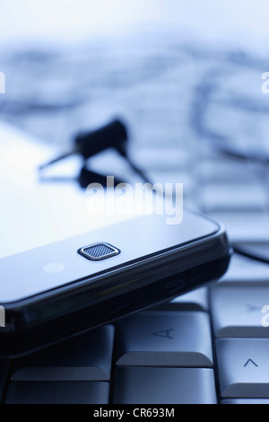 Handy auf Tastatur mit Kopfhörer im Büro, Nahaufnahme Stockfoto