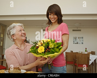 Deutschland, Köln, Frauen halten Blumenstrauß in Pflegeheim, Lächeln Stockfoto