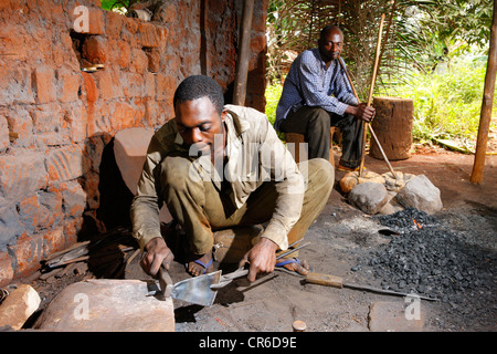 Smith macht ein Musikinstrument aus Schrott und ein anderer Mann Betrieb Balg, Babungo, Kamerun, Afrika Stockfoto