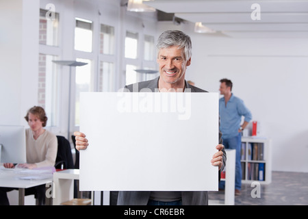 Deutschland, Bayern, München, reifer Mann hält Plakat im Büro Stockfoto