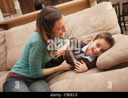 Mutter kitzeln ihres Sohnes (6-7) auf couch Stockfoto