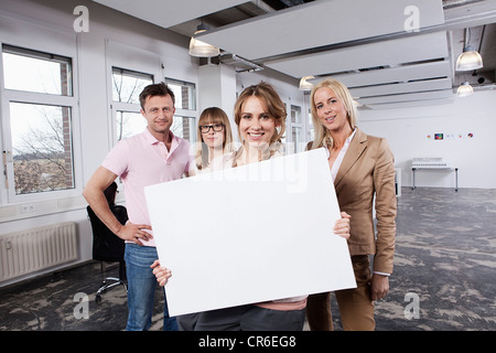 Deutschland, Bayern, München, junge Frau mit Schild mit Kollegen im Büro Stockfoto