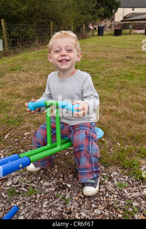 Zwei Jahre alten Jungen spielen auf einer Wippe, Devon, England, Vereinigtes Königreich. Stockfoto