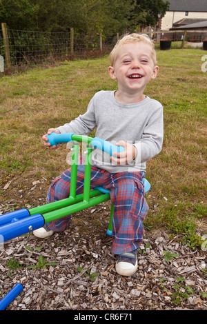 Zwei Jahre alten Jungen spielen auf einer Wippe, Devon, England, Vereinigtes Königreich. Stockfoto