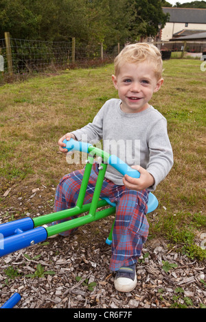 Zwei Jahre alten Jungen spielen auf einer Wippe, Devon, England, Vereinigtes Königreich. Stockfoto