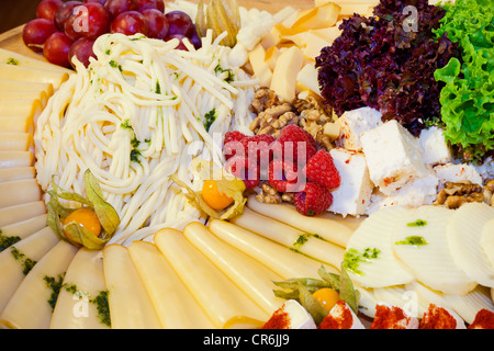 Käseauswahl mit Trauben, Himbeeren und Salat dekoriert Stockfoto