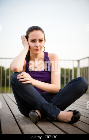 Outdoor-casual Portrait junge Frau sitzt am Boden Stockfoto