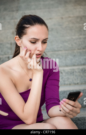 Junge besorgt und nervösen Frau halten Handys und Beißen Nägel Stockfoto