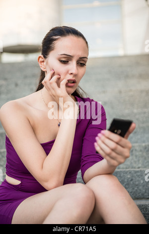 Junge besorgt und nervösen Frau halten Handys und Beißen Nägel Stockfoto