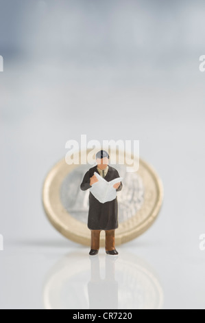 Geschäftsmann Figur hält Zeitung vor-Euro-Münze Stockfoto