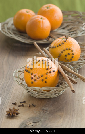 Orange mit Nelken und Zimtstange in Korb neben Sternanis auf Tisch besetzt Stockfoto