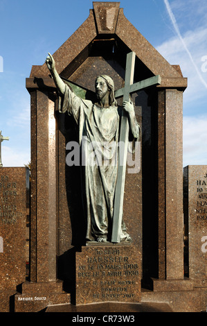 Grabstein mit einer Figur von Jesus vor blauem Himmel im Friedhof von Guebwiller, Route de Colmar, Guebwiller, Elsass, Frankreich Stockfoto