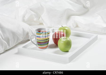 Tablett mit Tee und Äpfel auf Bett zum Frühstück, Nahaufnahme Stockfoto