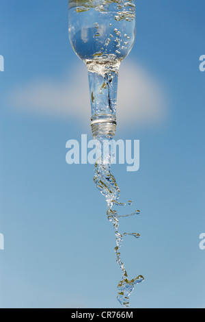 Gießen Wasser aus einer Glasflasche vor blauem Himmel Stockfoto