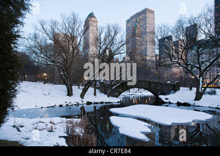 Vereinigte Staaten, New York City, Manhattan, Central Park im Winter unter dem Schnee, den Teich, Gapstow Brücke und die Türme der Stockfoto