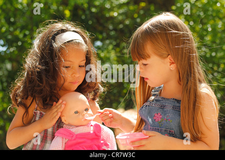 Kleine Mädchen eine Puppe füttern Stockfoto